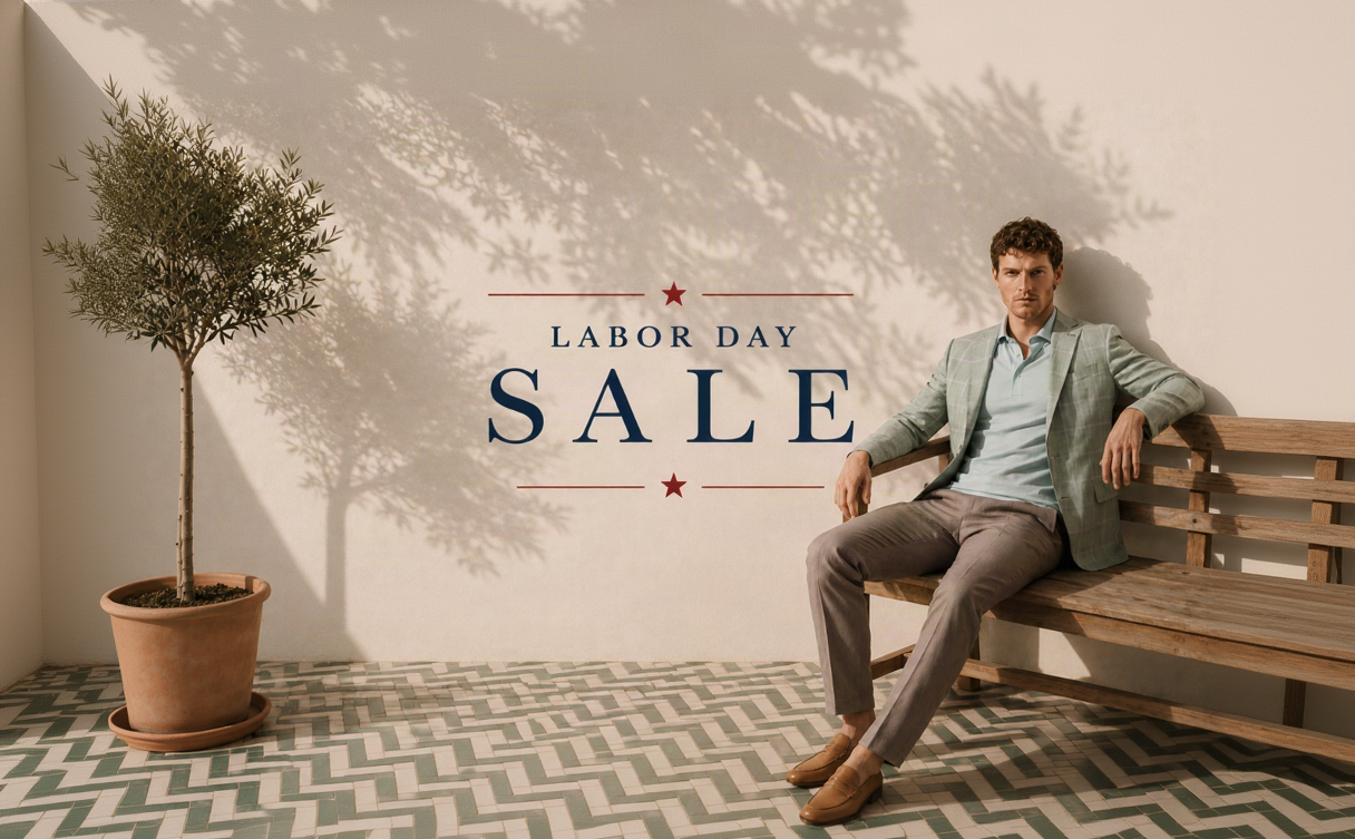 A man sits on a wooden bench against a sunlit wall, wearing a light sage green blazer, pale blue shirt, taupe trousers, and tan loafers. Large overlaid text reads 'LABOR DAY SALE' with small red stars.
