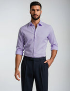 Man wearing a light purple dress shirt and dark pants on a plain background