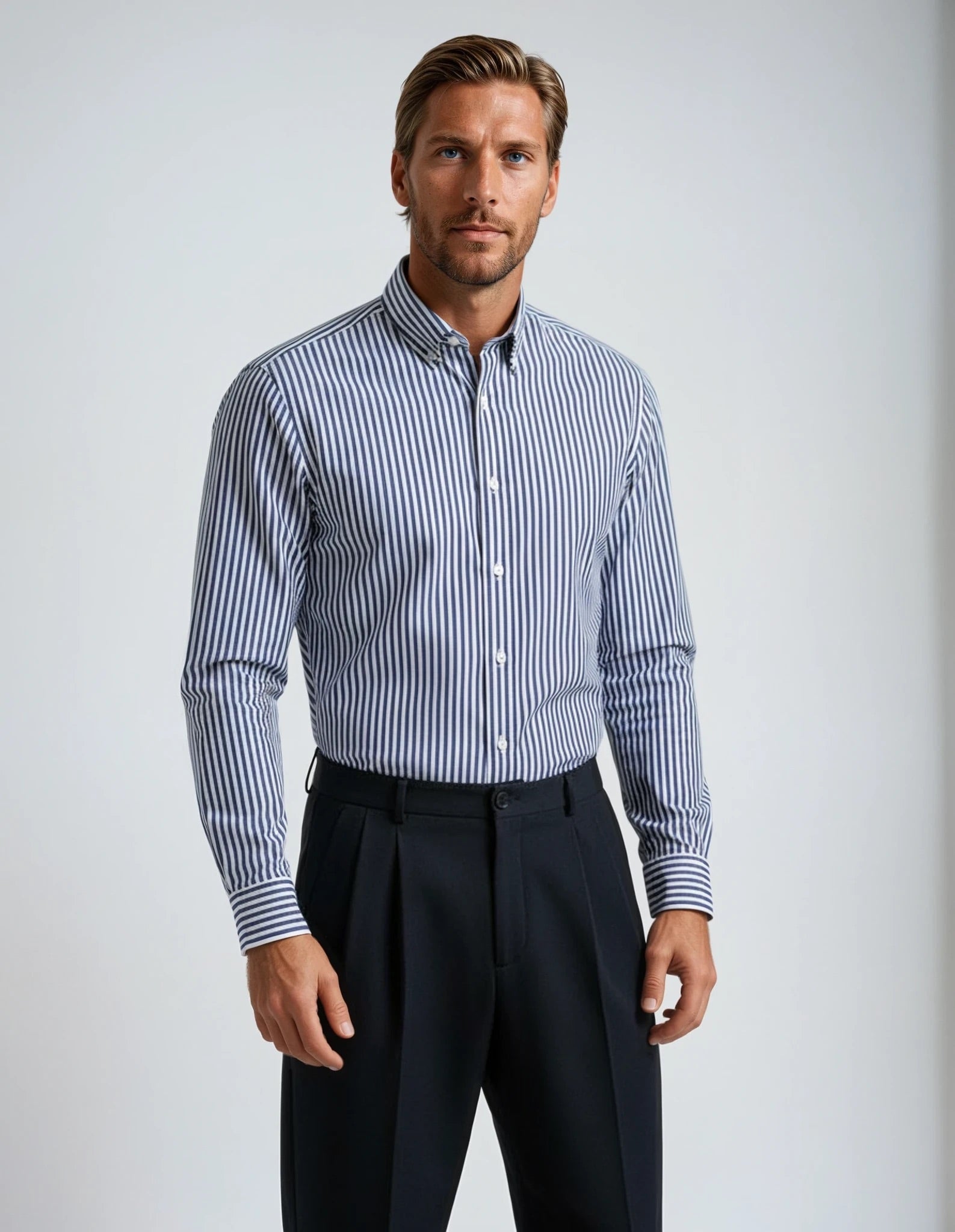 Man wearing a blue and white striped shirt with black pants on a light gray background