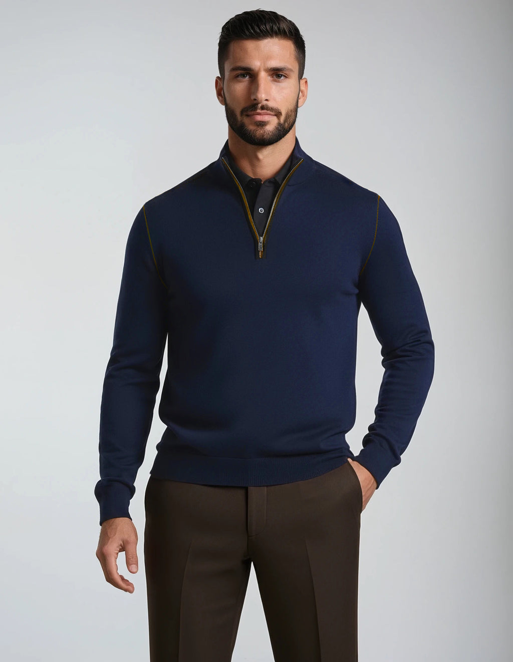 Man wearing a navy blue quarter-zip sweater and brown pants on a light gray background
