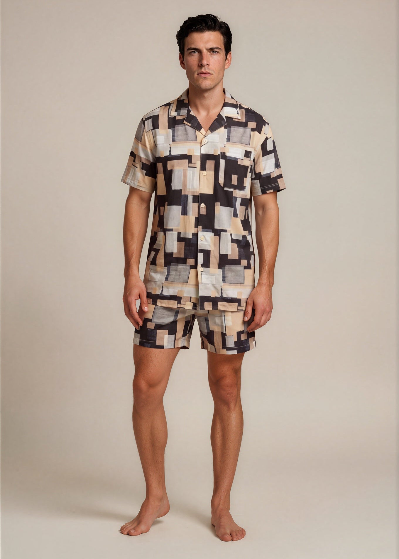 Man wearing a patterned shirt and shorts set against a plain background