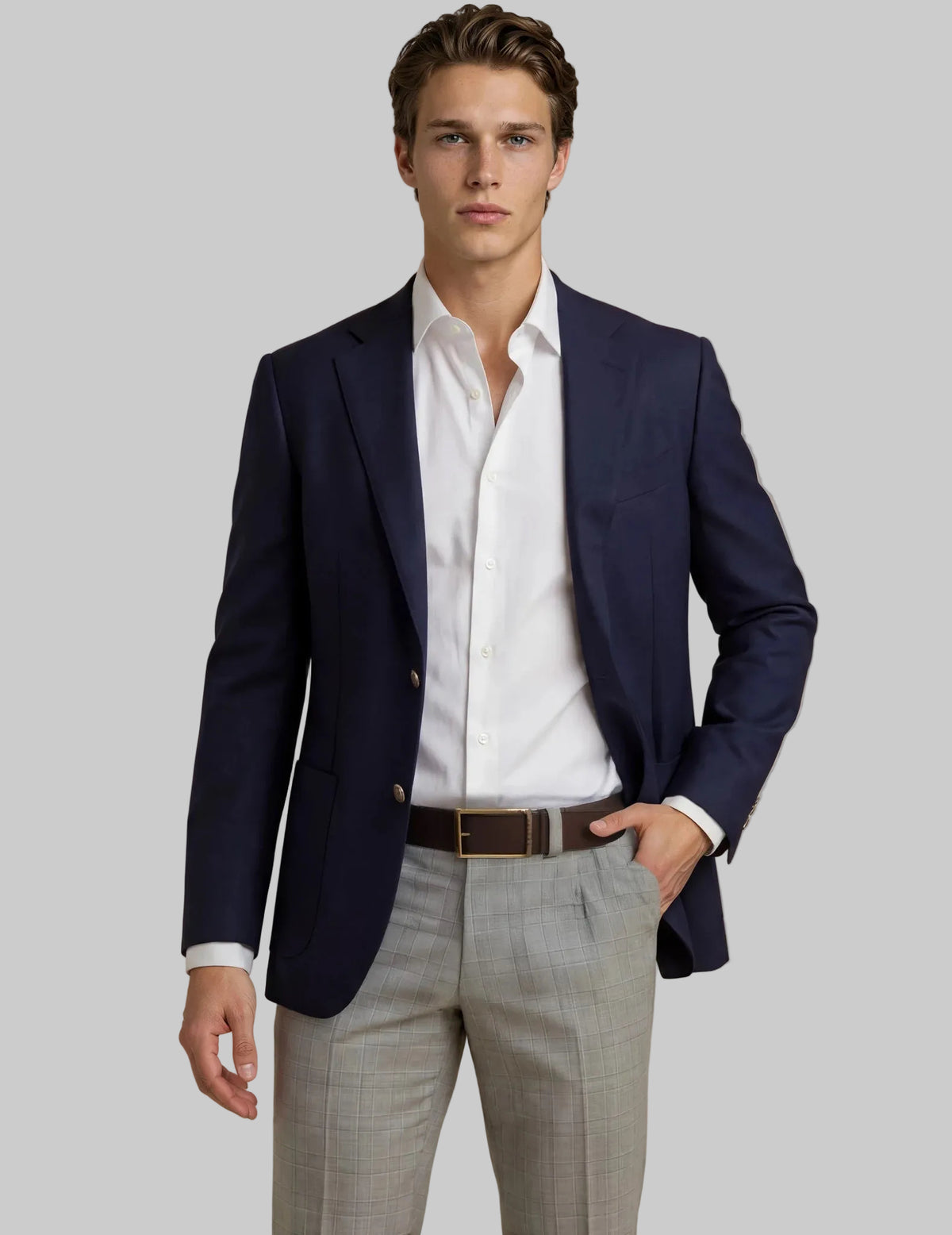 Man wearing a navy blazer, white shirt, and light gray pants on a beige background