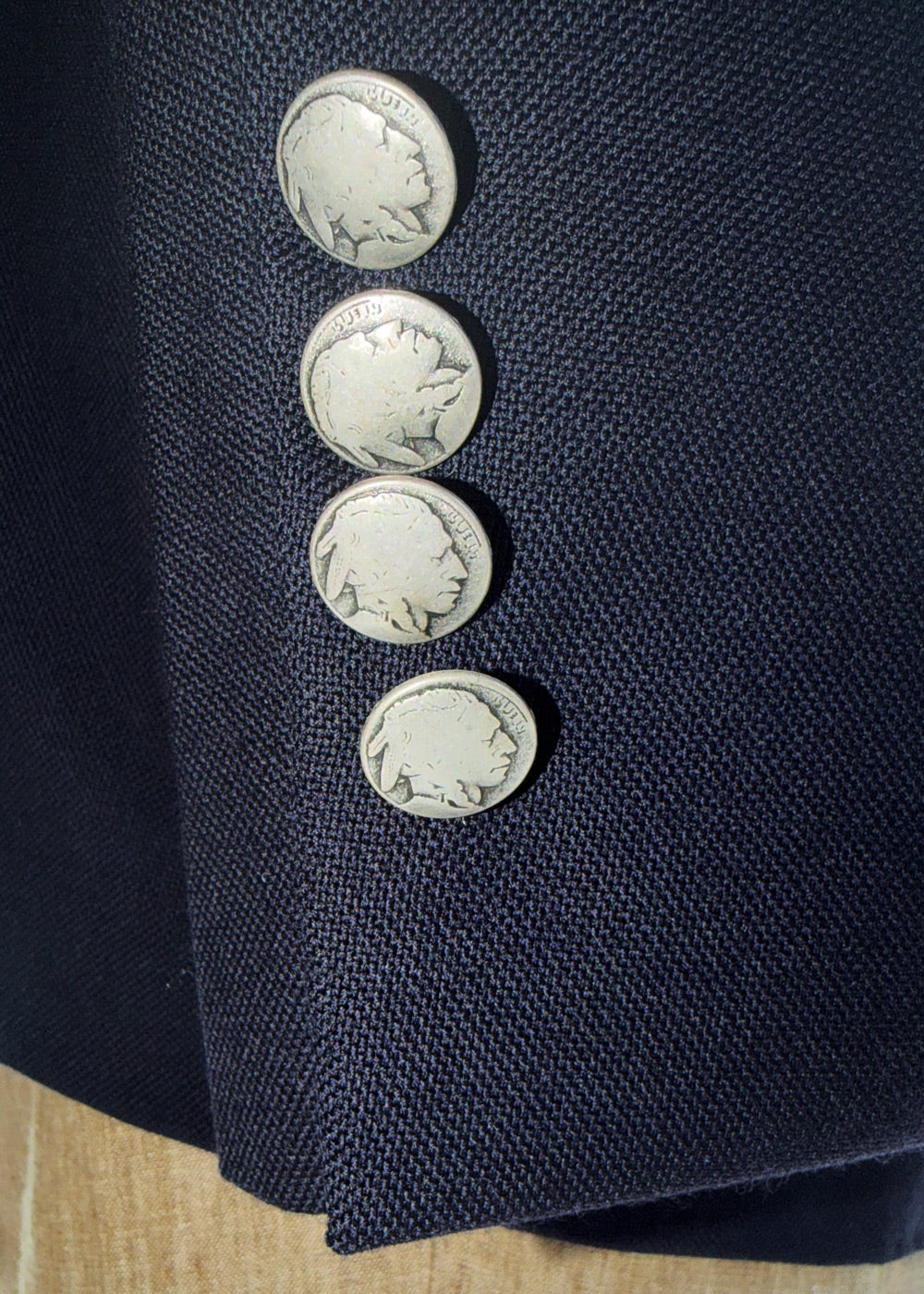 Close-up of a navy blue hopsack fabric with silver buttons featuring a buffalo nickel design.