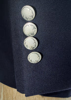 Close-up of a navy blue hopsack fabric with silver buttons featuring a buffalo nickel design.