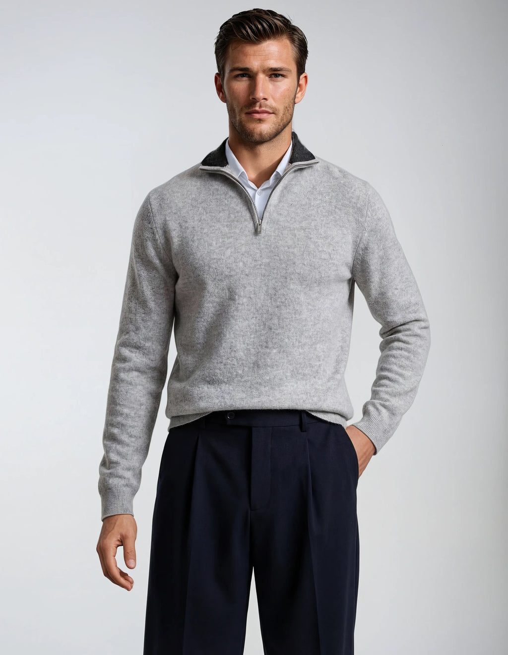 Man wearing a gray sweater with a quarter zip and dark pants on a light gray background