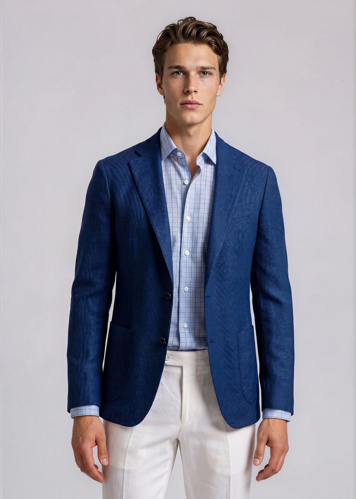 Man wearing a blue blazer, light blue shirt, and white pants against a plain background