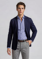 Man wearing a navy blazer, patterned shirt, and gray pants on a light gray background