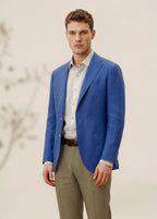 Man wearing a blue blazer, white shirt, and beige pants against a neutral background