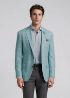 Man wearing a light blue blazer, gray pants, and a striped shirt on a plain background