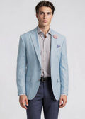 Man wearing a light blue blazer over a striped shirt with a white background