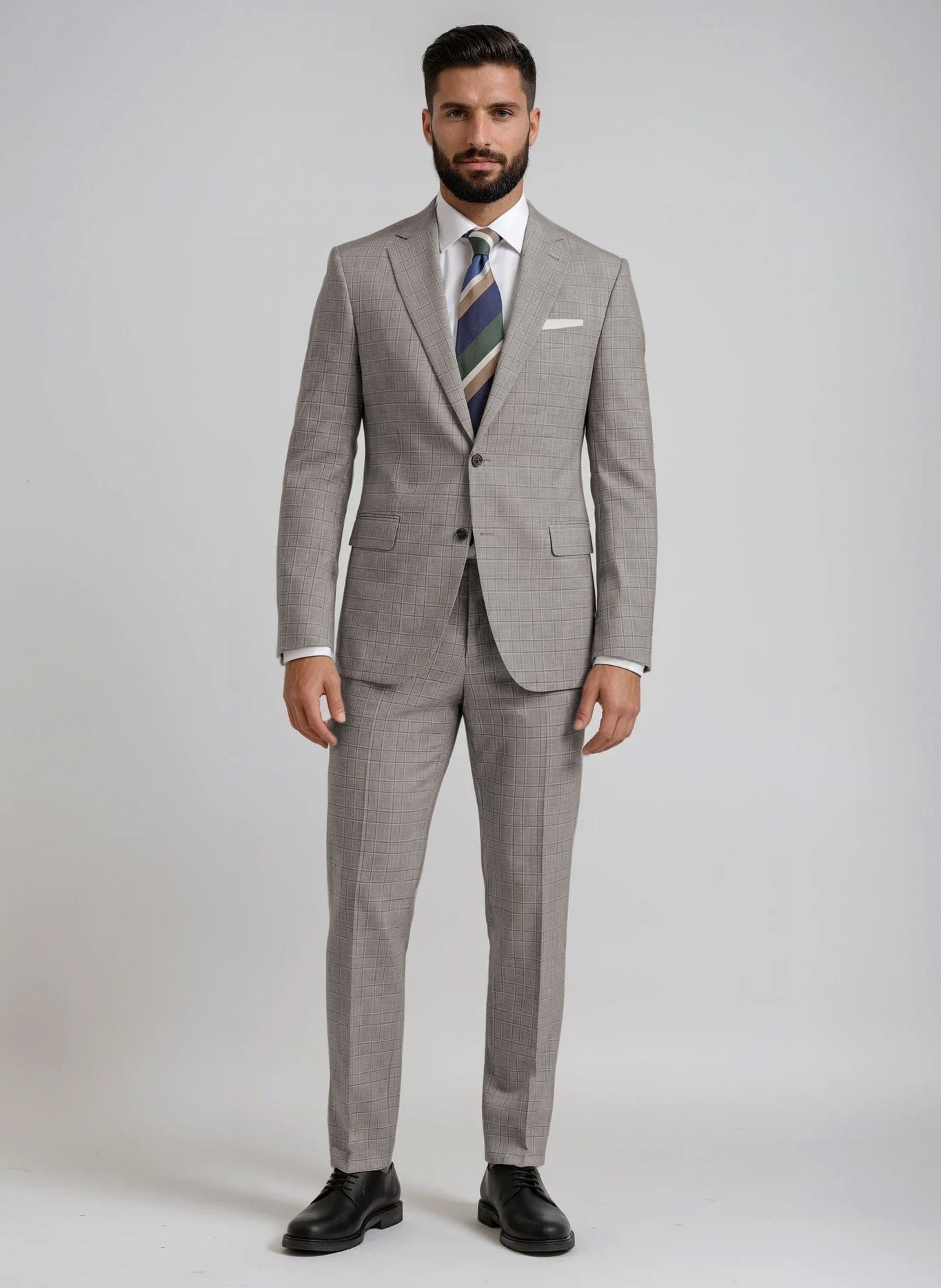 Man wearing a gray/brown glen plaid suit with a striped tie on a plain background