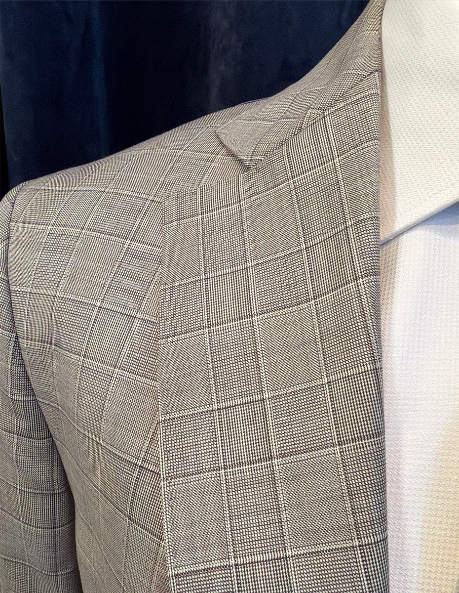 Gray/brown checkered suit jacket on a mannequin against a dark background