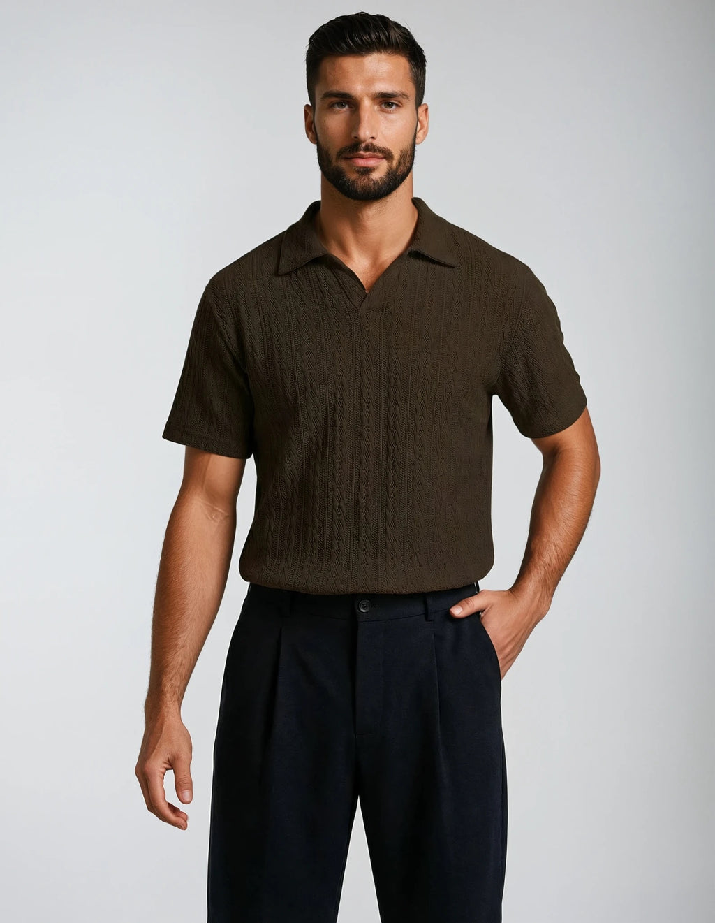 Man wearing a brown cable knit polo shirt and dark pants on a light gray background