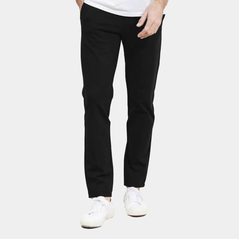 Lower half of model wearing black pants and white sneakers over pale gray background