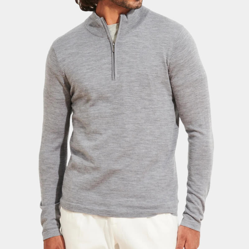 Model wearing mid-gray zipped sweater and casual white pants over light gray background