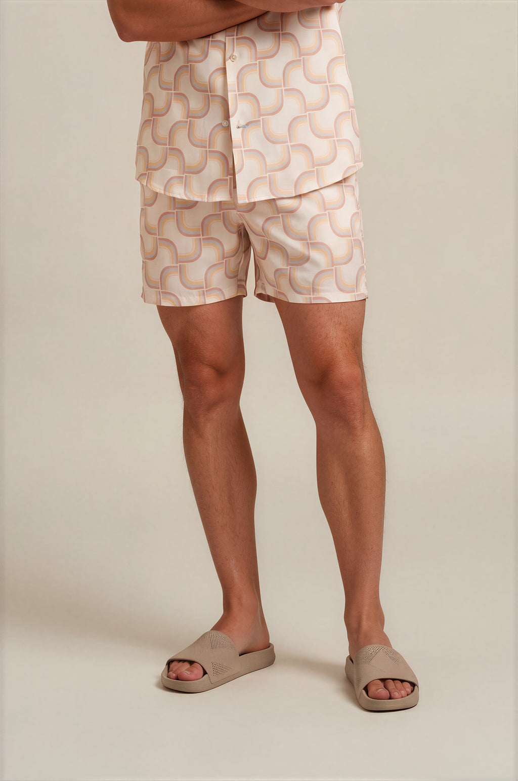 Person wearing beige shorts with a geometric pattern on a plain background