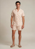 Man wearing a matching shirt and shorts set with a light pattern on a plain background