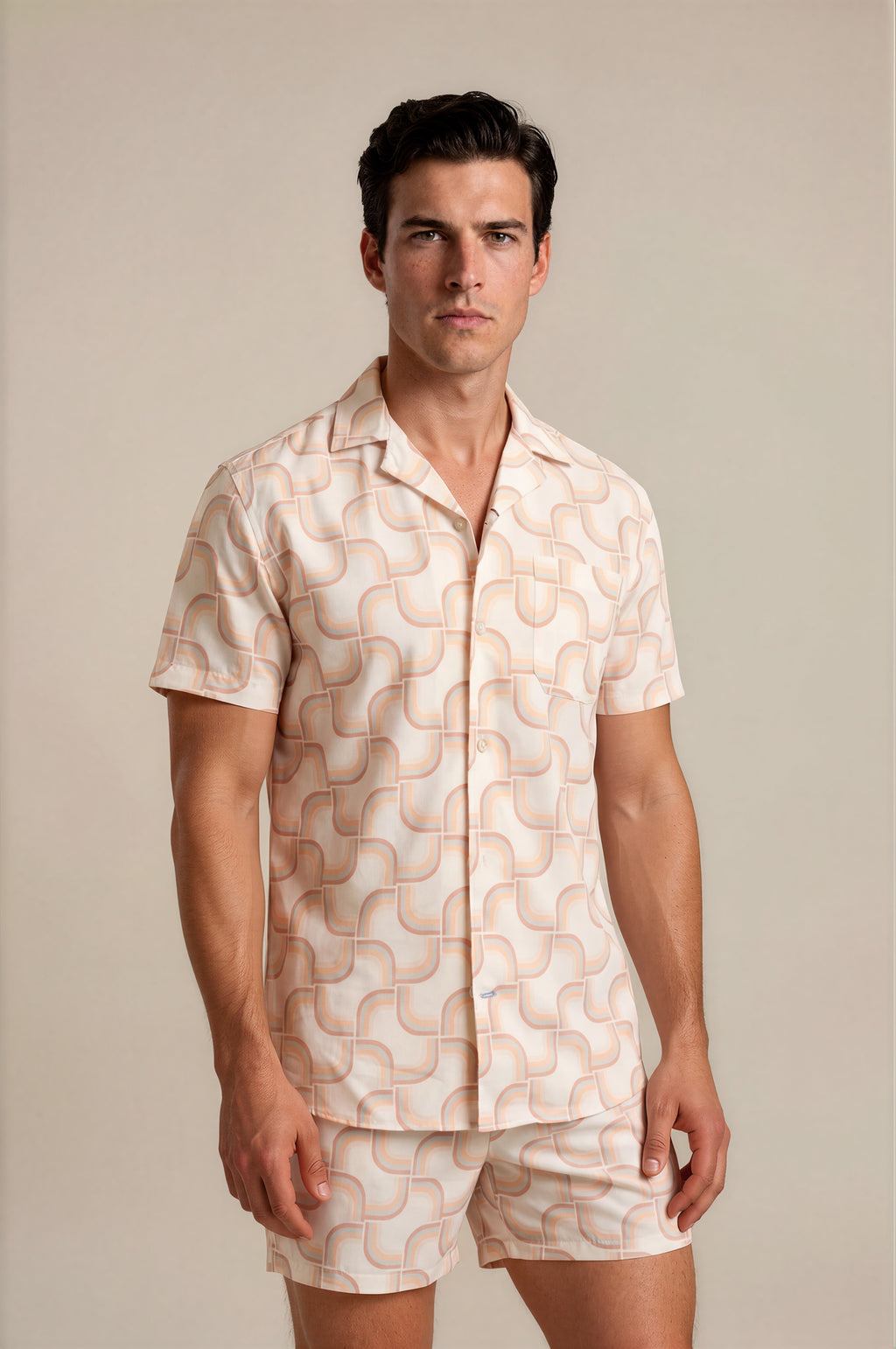 Man wearing a patterned shirt and shorts set against a plain background