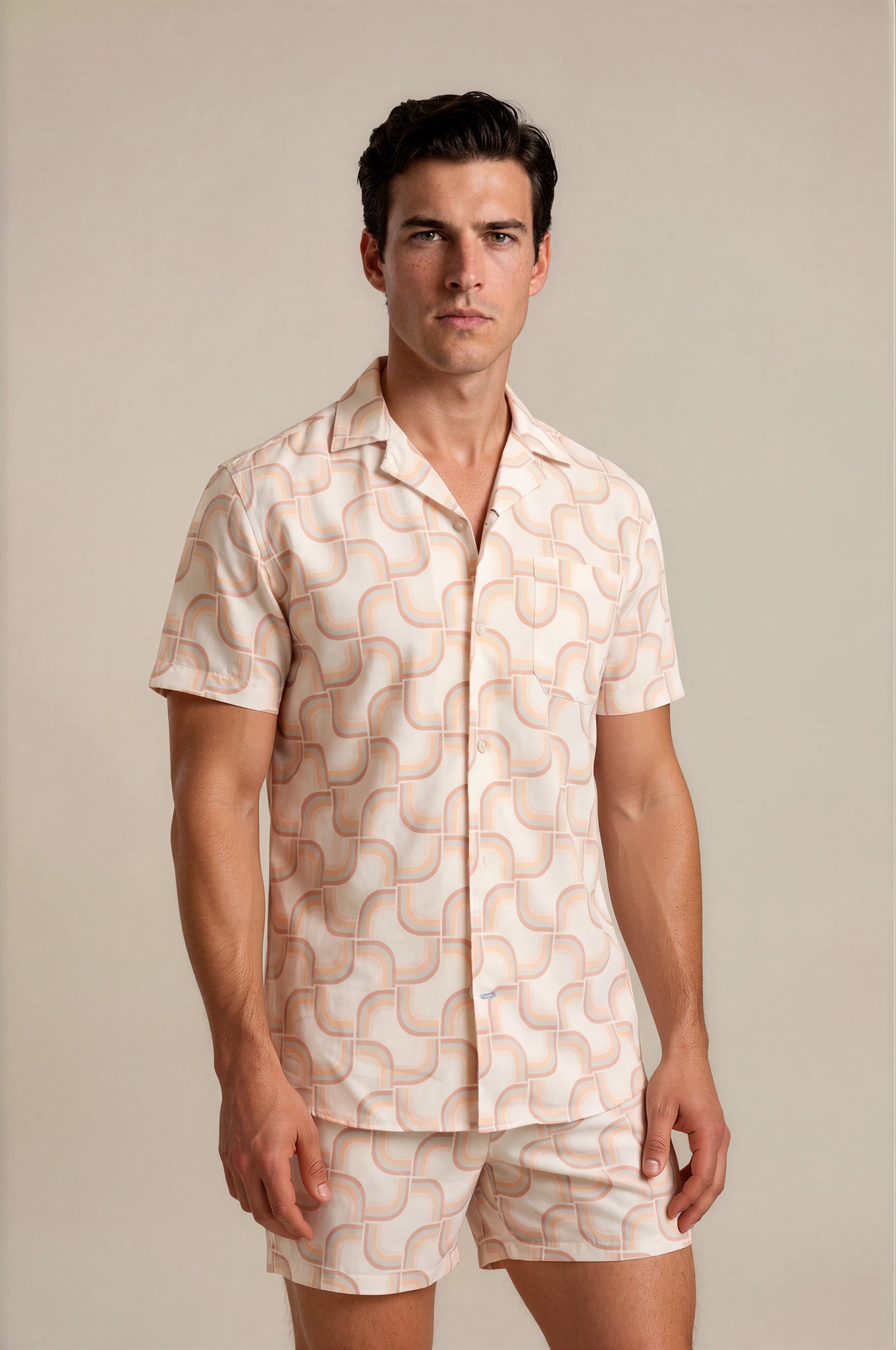 Man wearing a patterned shirt and shorts set against a plain background