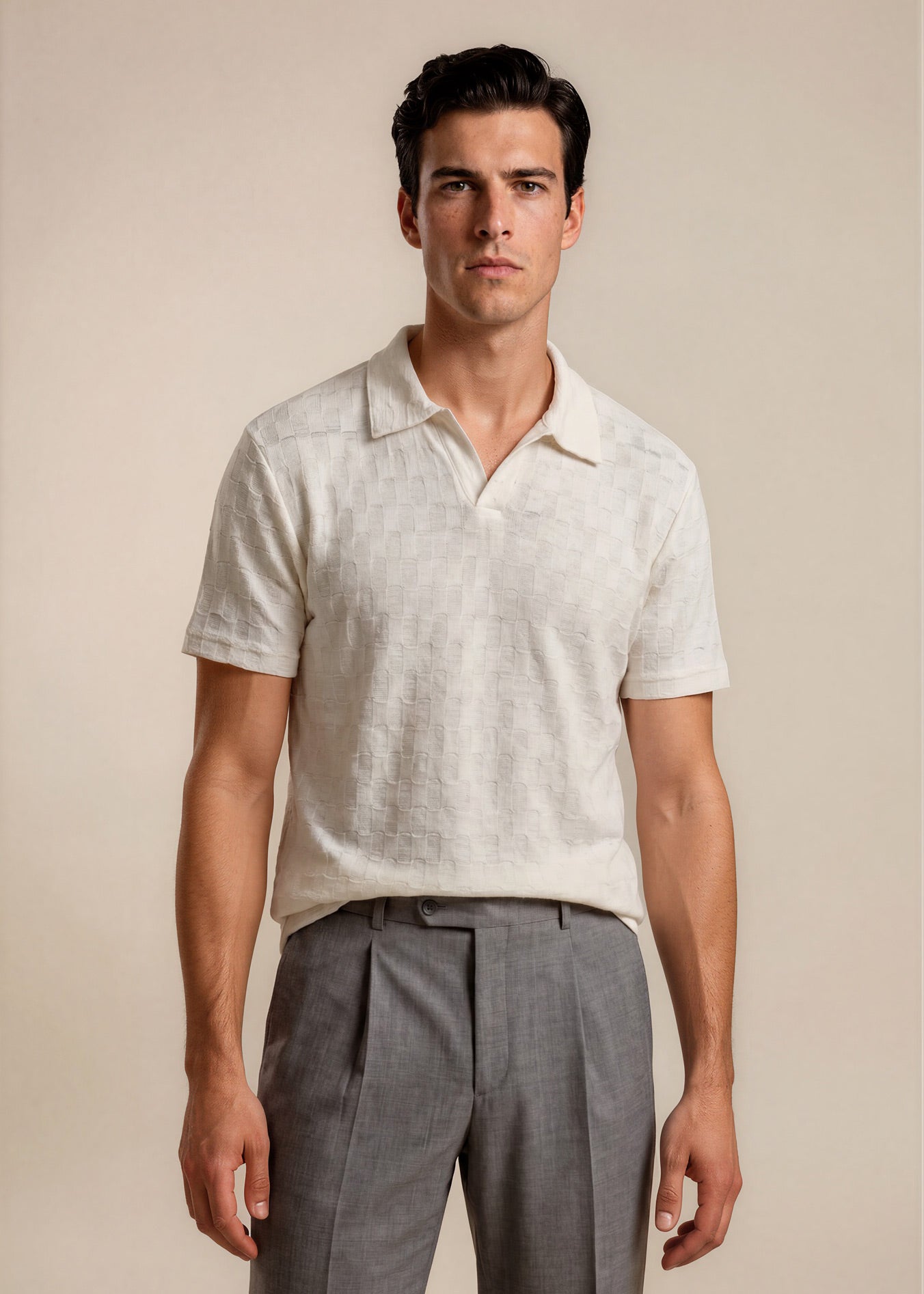 Man wearing a light-colored polo shirt and gray pants against a beige background