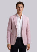 Man wearing a light pink blazer over a white shirt with a gray background