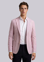 Man wearing a light pink blazer over a white shirt with a gray background