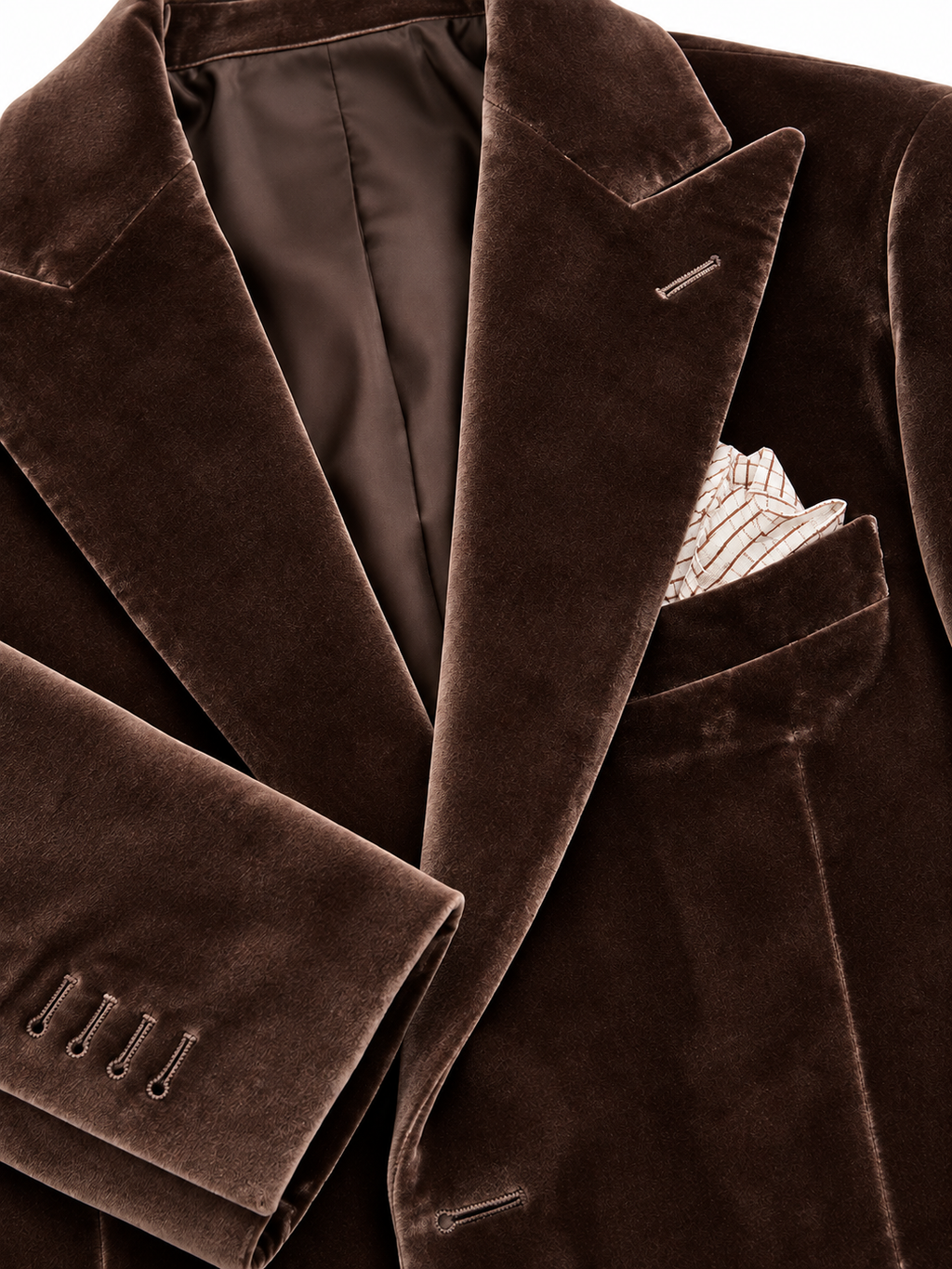 Close-up of a dark brown velvet blazer with a matching pocket square in the breast pocket, featuring lapel tabs and cuff buttons.