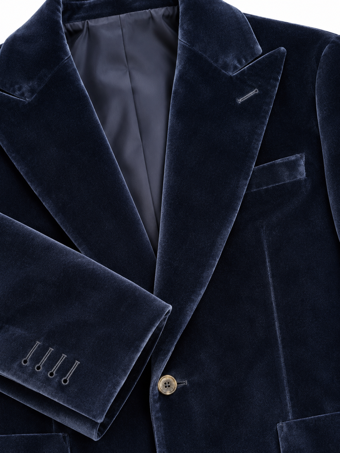 Close-up of a dark navy blue velvet blazer jacket, showing the rich texture of the fabric, a single gold-toned button, and the interior dark lining.