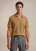 Man wearing a brown short-sleeve shirt and gray pants against a beige background