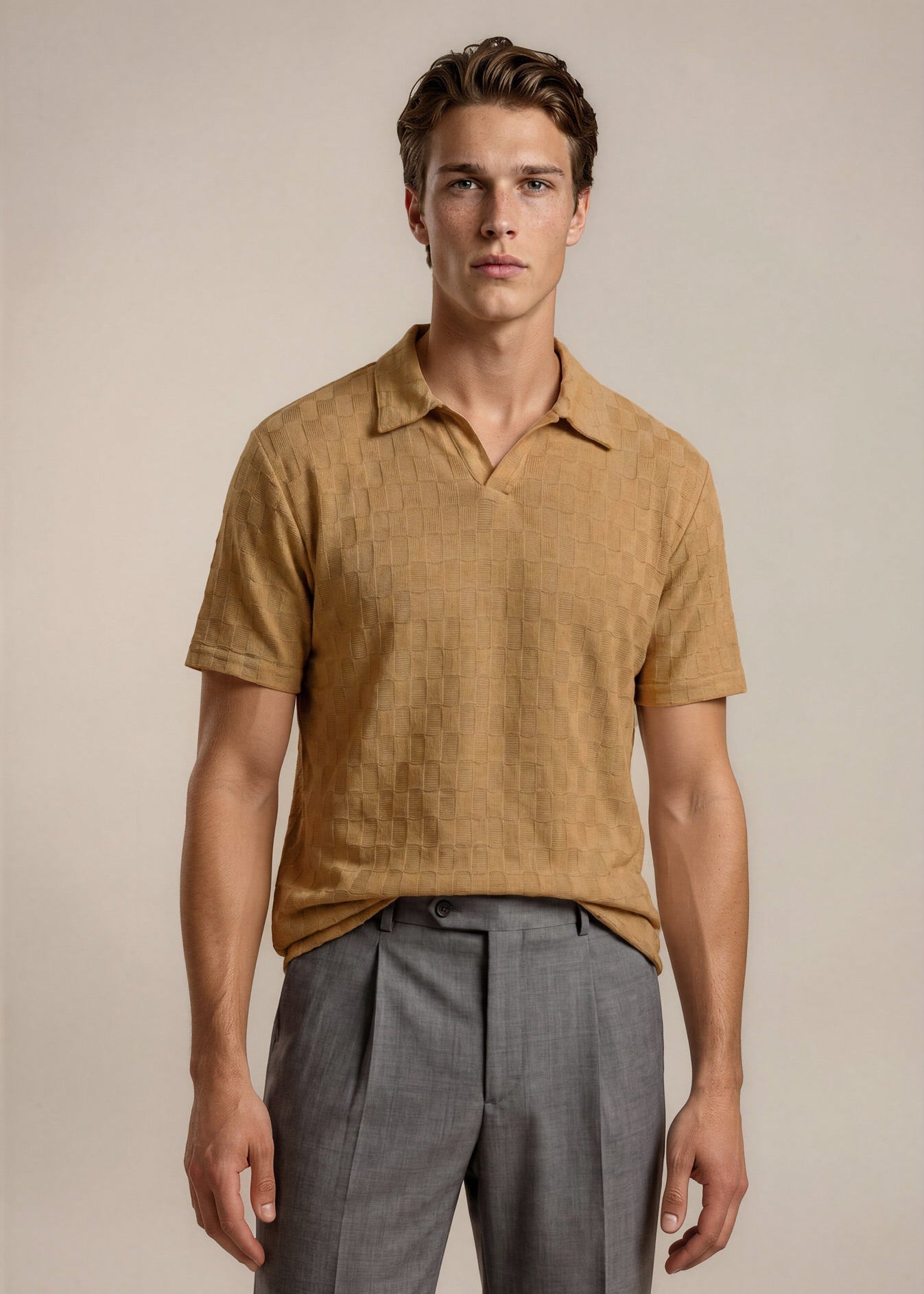 Man wearing a brown short-sleeve shirt and gray pants against a beige background