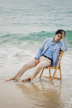 Man in sky blazer sitting on a wooden chair in the water at the beach