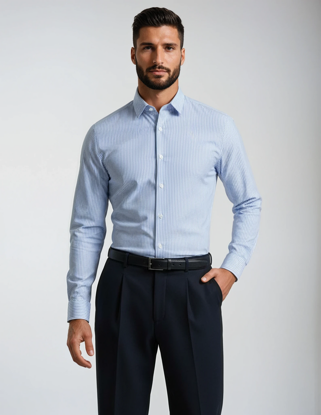 Man wearing a light blue striped dress shirt and dark pants on a gray background