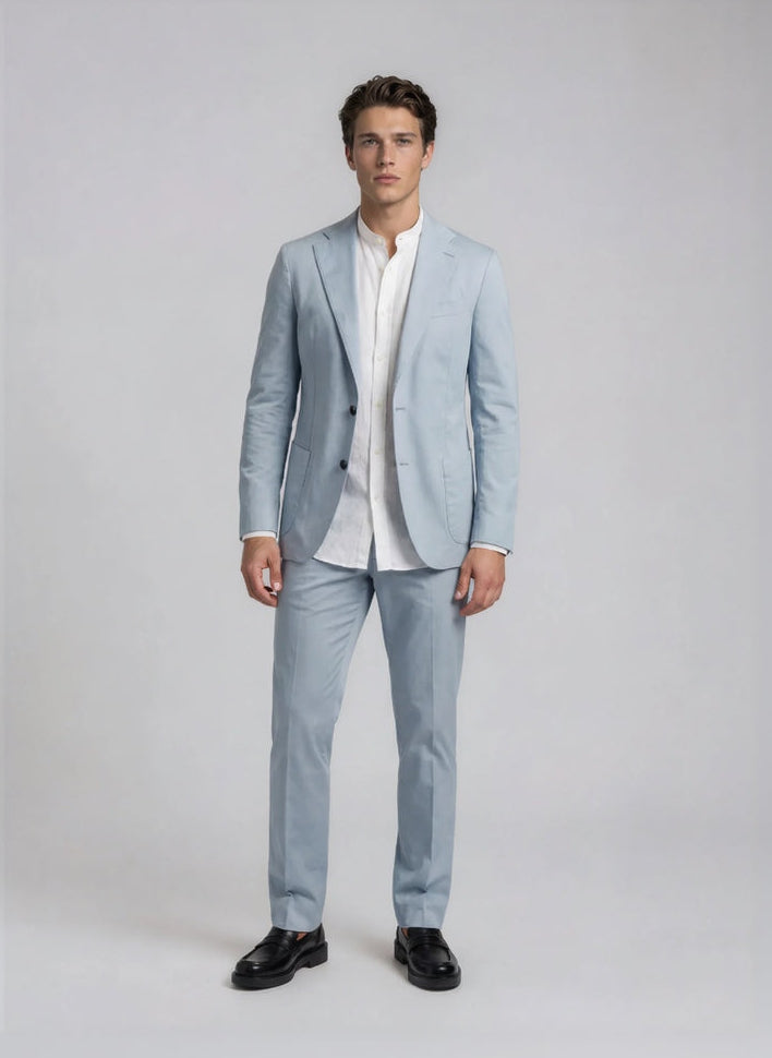 Man wearing a light blue suit with a white shirt on a plain background