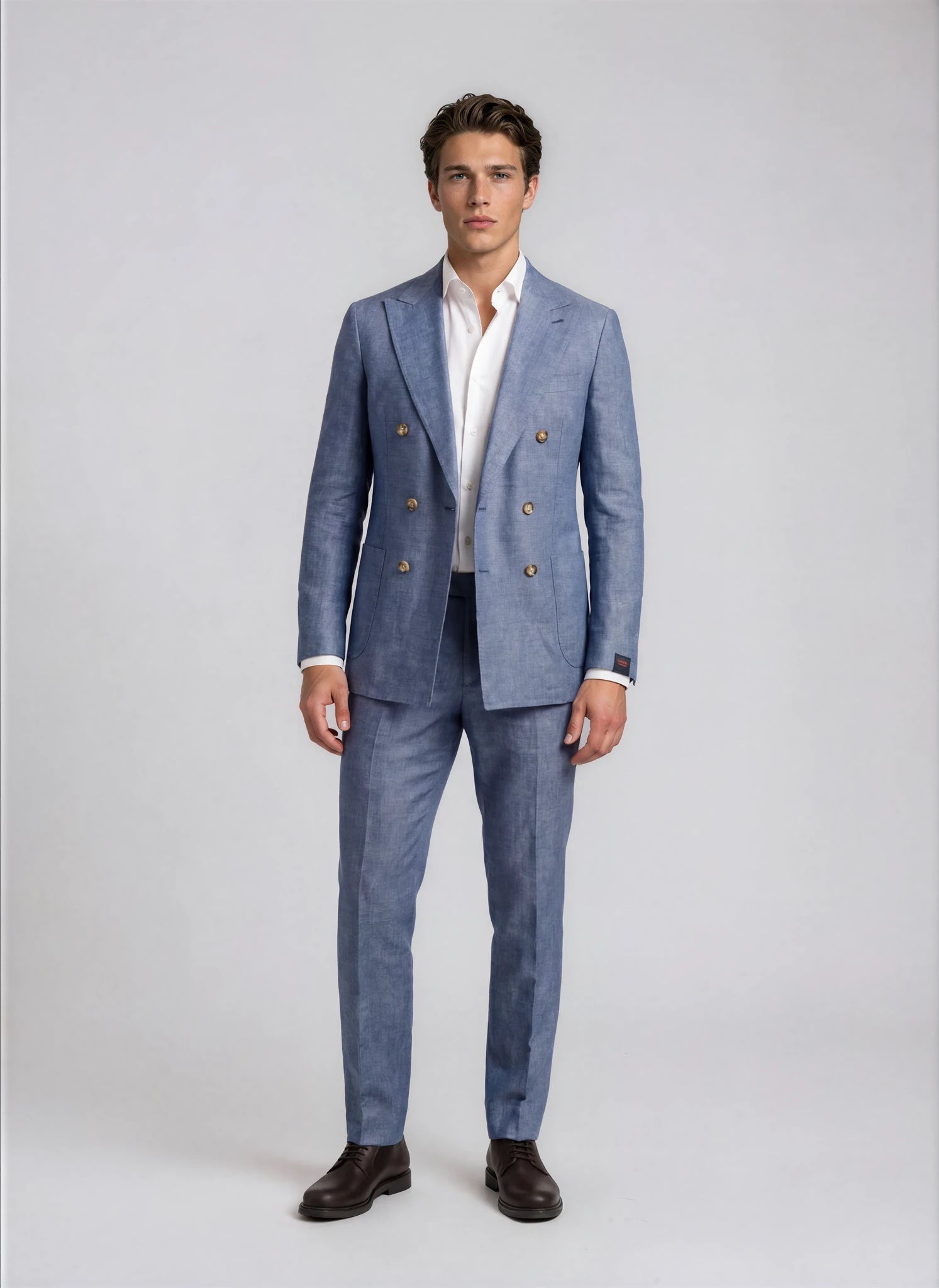 Man wearing a blue suit with tan buttons on a white background