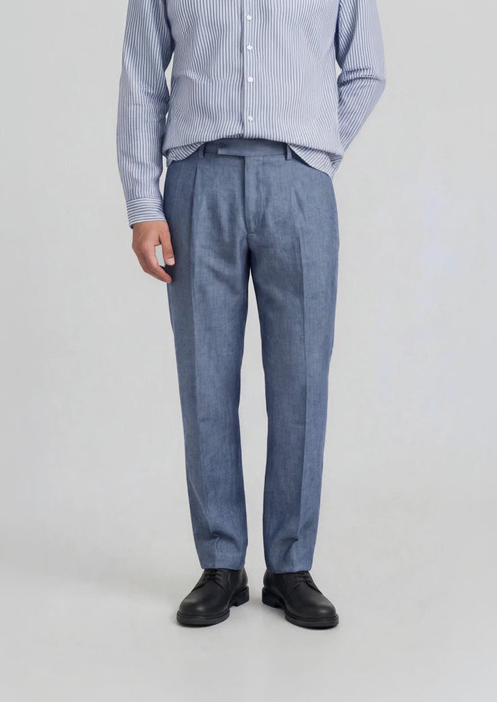 Man wearing a light blue striped shirt and dark sky blue chambray linen pants on a white background